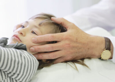 Medico osteopata che tiene la testa ad un bambino